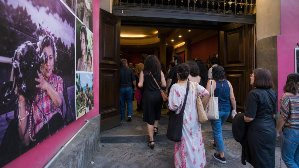 Público observa una proyección cinematográfica en una sala cultural durante una muestra dedicada a mujeres creadoras.
